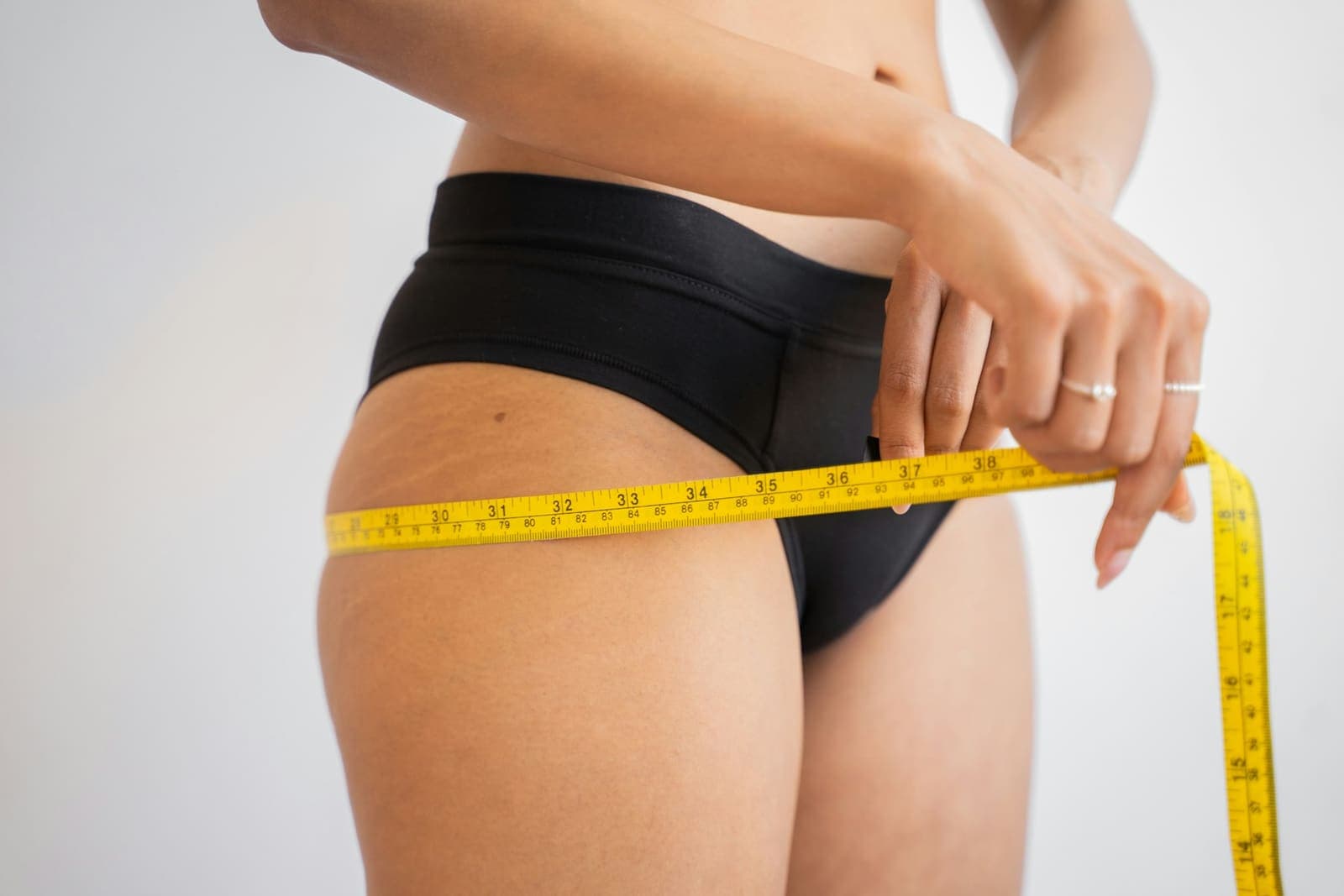 Person measuring their waist with a yellow tape measure