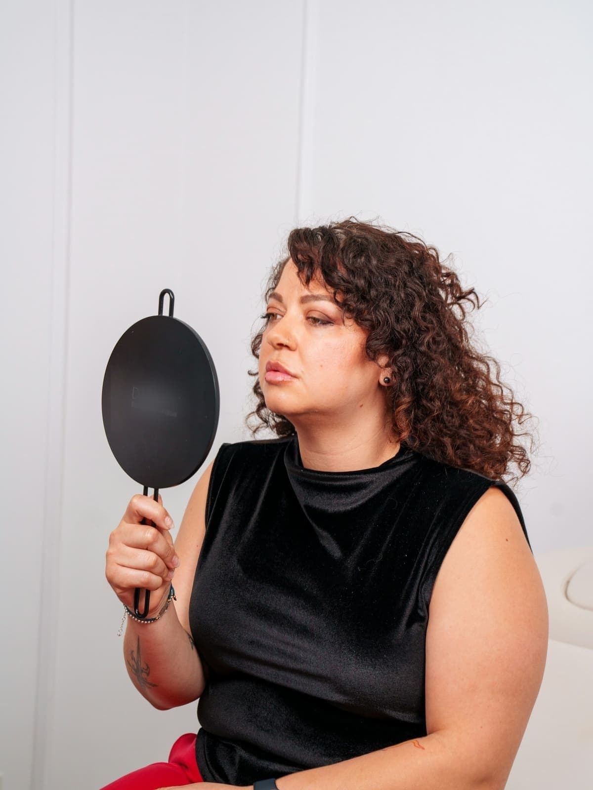 Woman with curly hair checking her results in a hand mirror