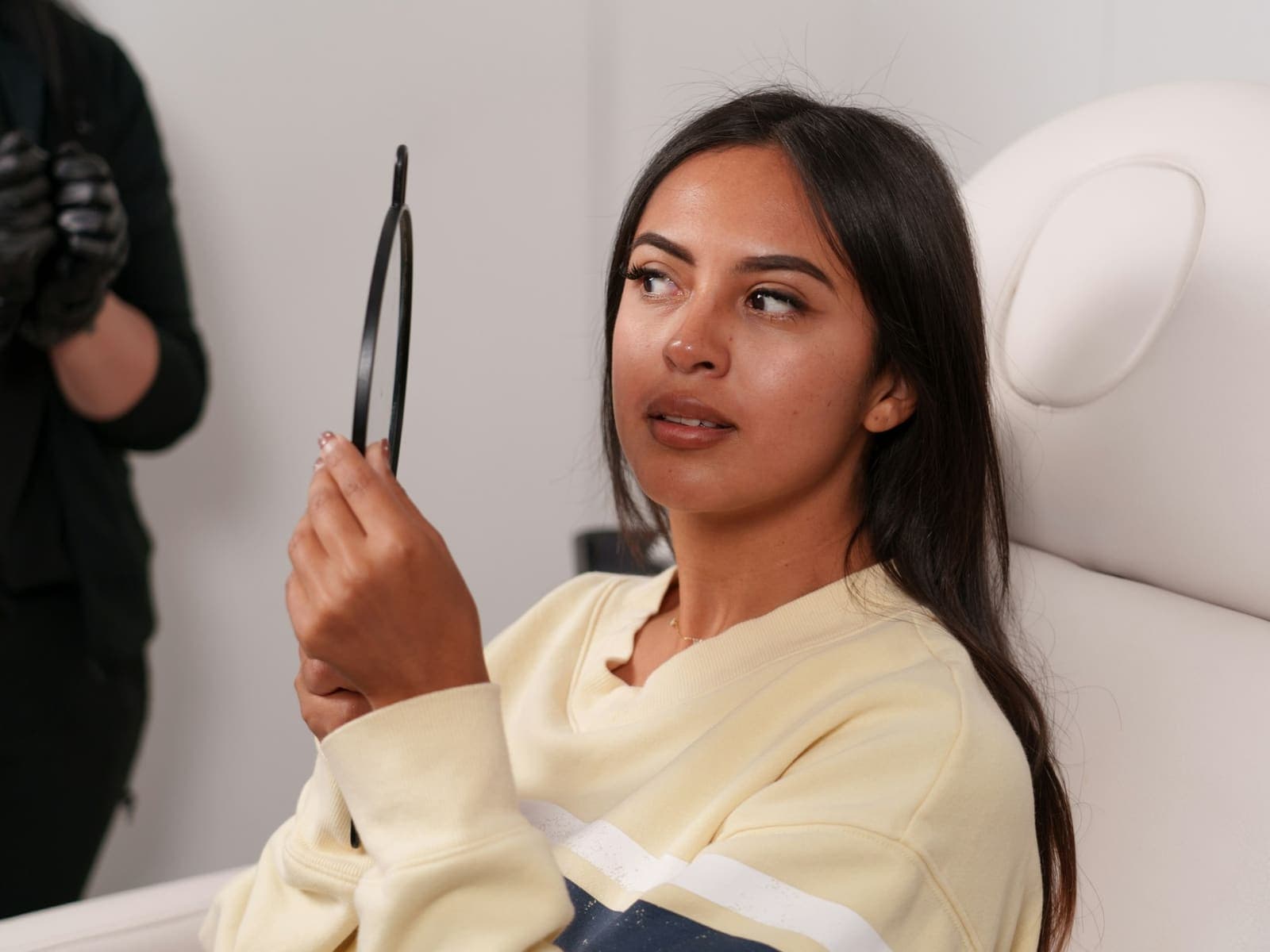 Client in a treatment chair looking into a hand mirror