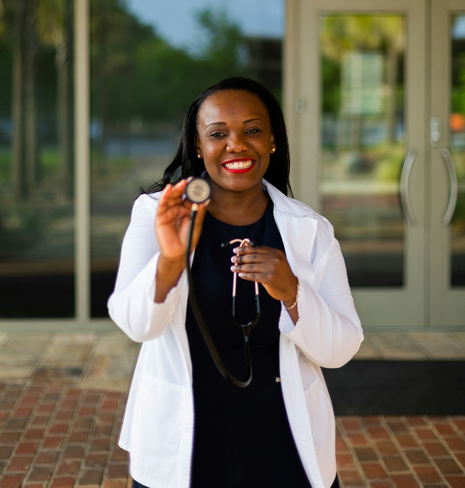 Smiling provider in a white coat holding a stethoscope